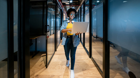 Woman walking with laptop in office