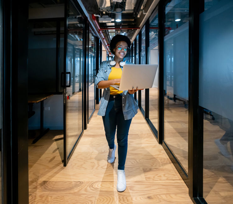 Woman walking with laptop in office